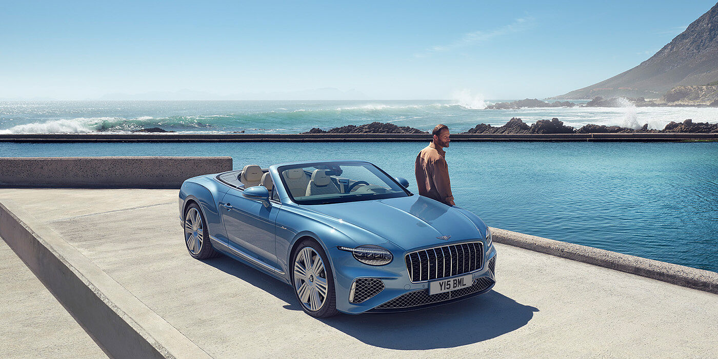 Bentley Hong Kong - Kam Lung New Bentley Continental GTC Azure convertible front view in Light Windsor blue paint with 22 inch ten spoke wheels parked by the sea in the sunshine