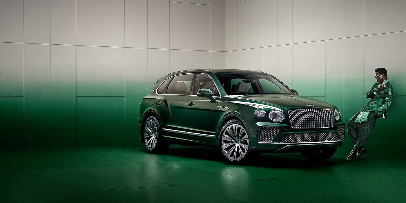 Bentley Hong Kong - Kam Lung Wisdom K leans against wall next to Bentley Bentayga Extended Wheelbase Atelier Edition SUV in Light Emerald green paint