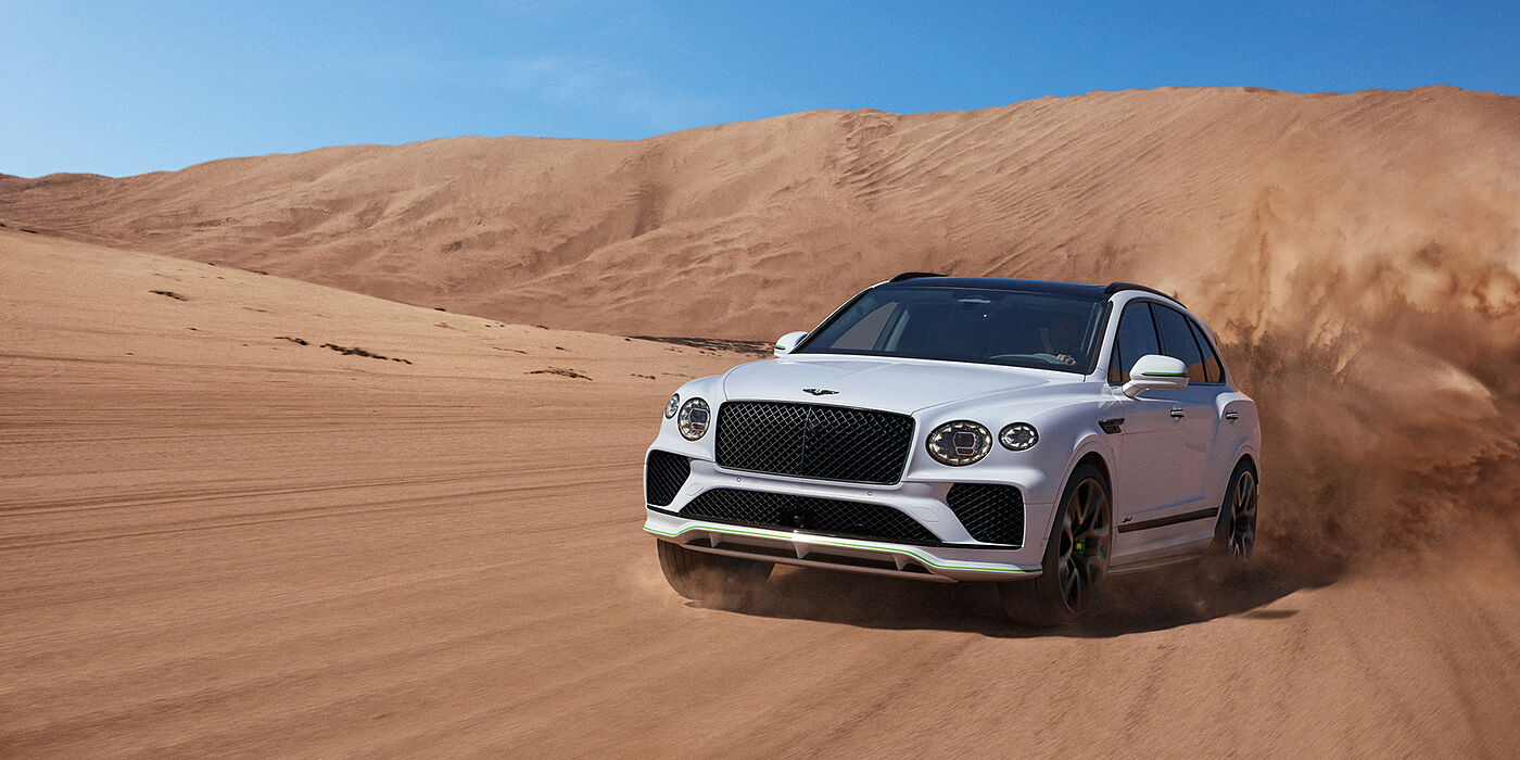 Bentley Hong Kong - Kam Lung Bentley Bentayga Speed SUV front three quarter in Snow Quarts Pearlescent by Mulliner white paint driving dynamically through the desert