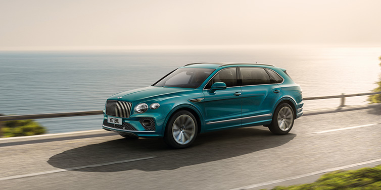 Bentley Hong Kong - Kam Lung Bentley Bentayga Extended Wheelbase Azure SUV in Topaz blue paint driving dynamically by the ocean
