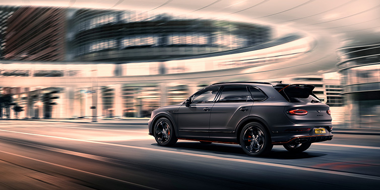 Bentley Hong Kong - Kam Lung Bentley Bentayga S Black Edition SUV rear three quarter in Anthracite Satin paint driving dynamically through a city at night