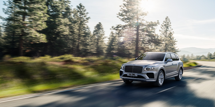 Bentley Hong Kong - Kam Lung Bentley Bentayga SUV front three quarter in Moonbeam silver paint driving dynamically along a tree-lined road