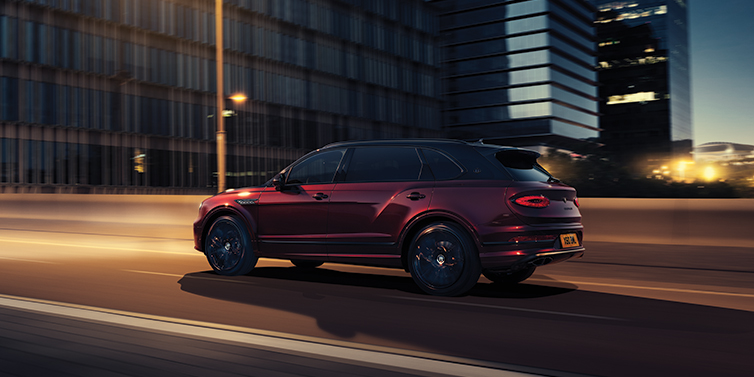 Bentley Hong Kong - Kam Lung Bentley Bentayga Extended Wheelbase Mulliner SUV in Cricket Ball red paint driving dynamically in city at night