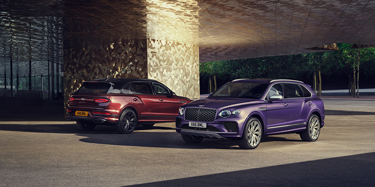 Bentley Hong Kong - Kam Lung A duo of Bentley Bentayga Extended Wheelbase Mulliner SUVs parked in a city environment, with Tanzanite Purple and Cricket Ball red exterior paint